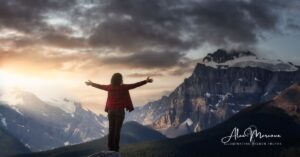 Person with arms open wide on mountain top symbolizing surrender
